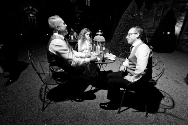 A black and white photo of three people sitting around a table eating