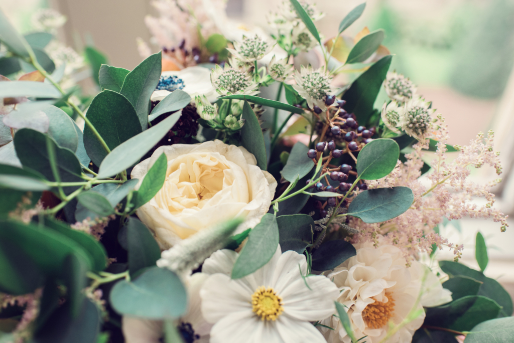 A bouquet of cream flowers and muted green foliage.