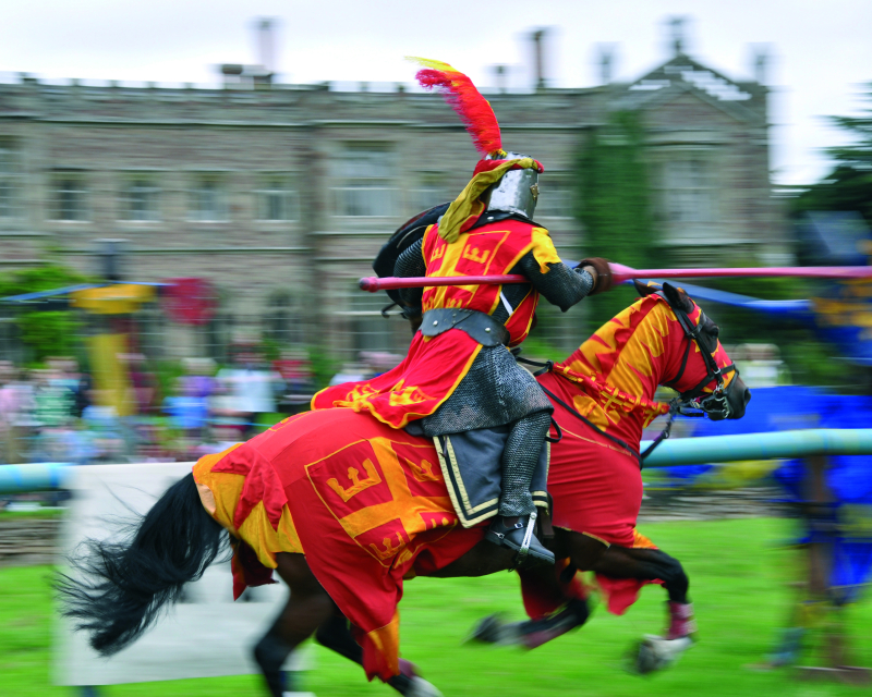 A knight in mail and red tabards jousting.