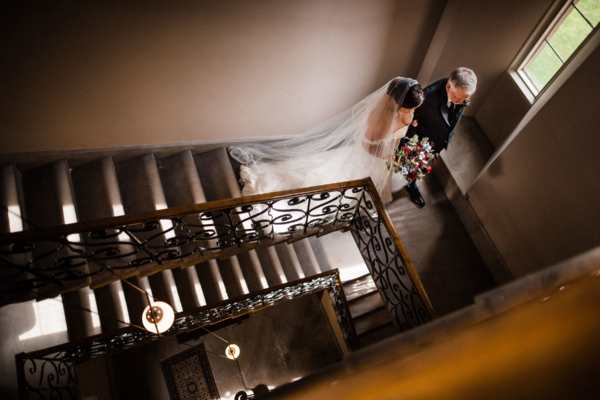 Bride and father of the bride walk down the cantilever staircase