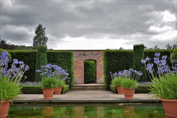 Doorway across water and paths with pots of purple flowers