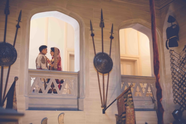 A couple looking into each other's eyes, standing in the archway of a balcony.