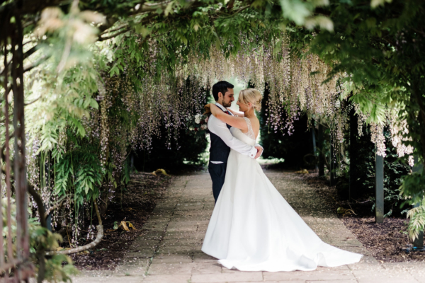 Wedding couple under the wisteria arch