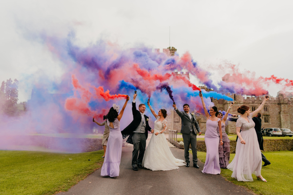 Wedding guests outside the castle with coloured smoke.