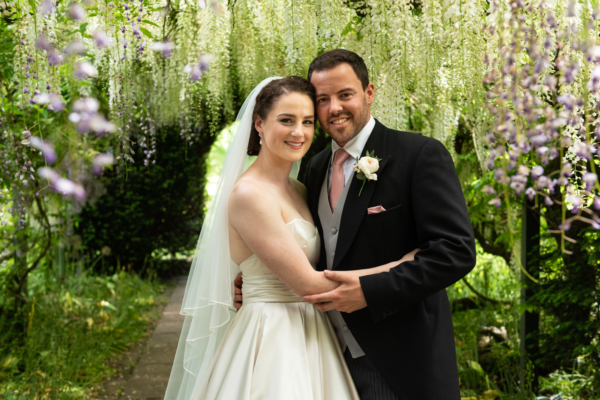 Wedding couple under wisteria arch