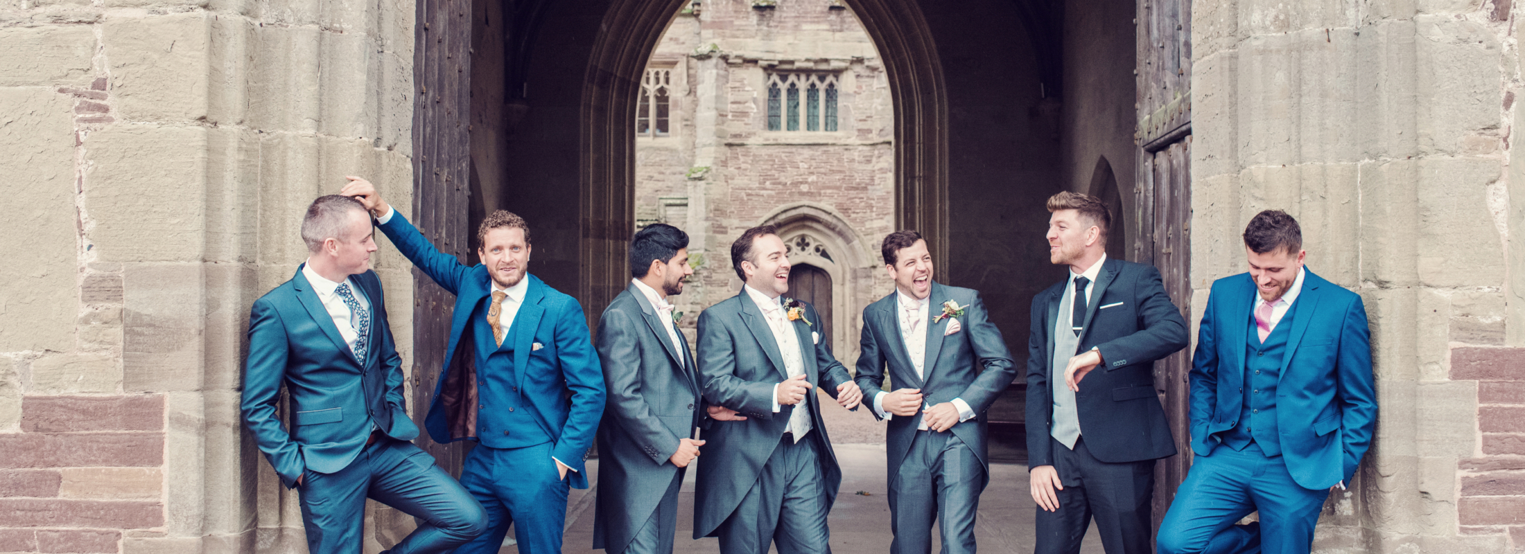 A groom and his groomsmen laughing in a castle doorway