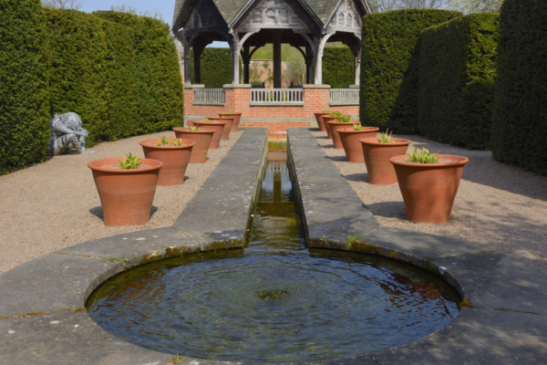 A circular water feature, leading down in a narrow channel to a pavilion