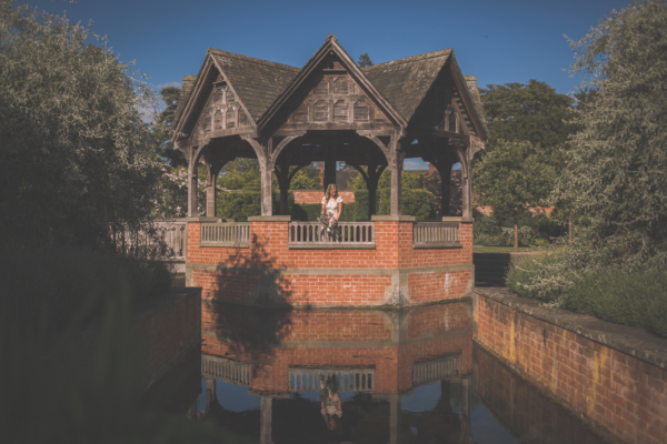 Bride in the centre of pavilion surrounded by reflecting water at Hampton Court Castle.