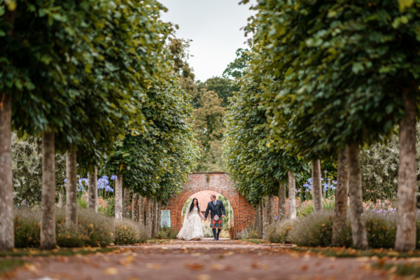 Wedding couple walking down avenue of trees