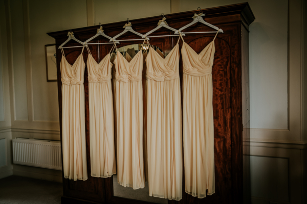 5 yellow bridesmaid dresses hung in bridal suite