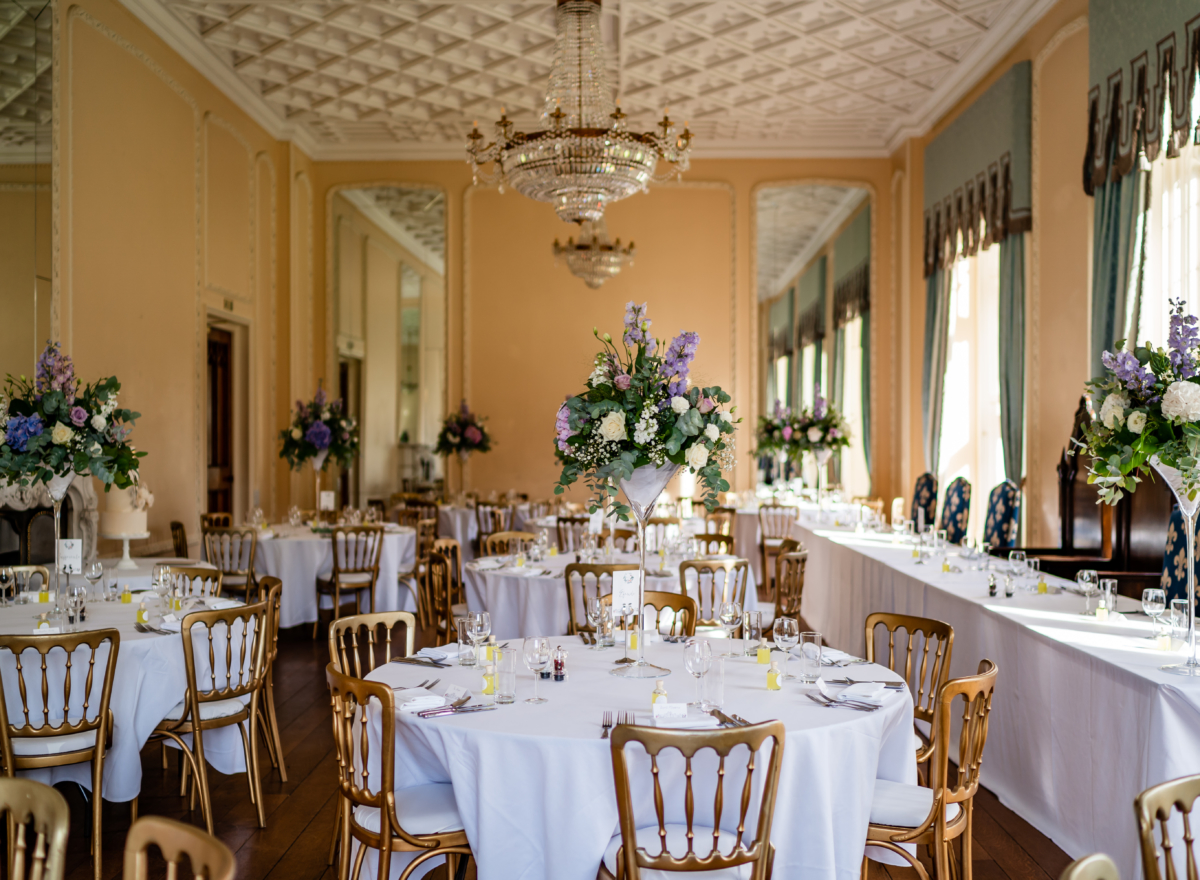 Ballroom dressed for wedding with floral centrepieces