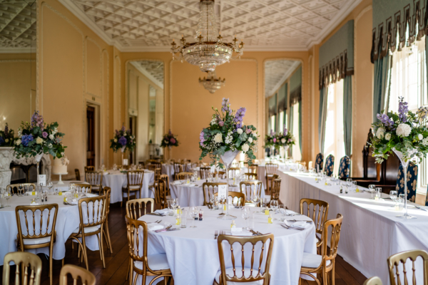 Ballroom dressed for wedding reception with floral centrepieces