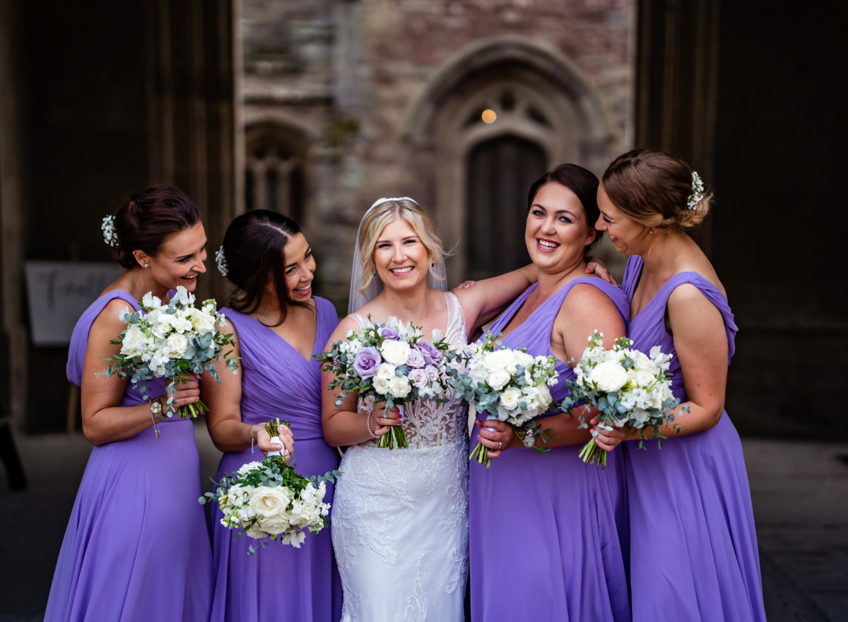 Bride smiles for photo with bridesmaids in draw through