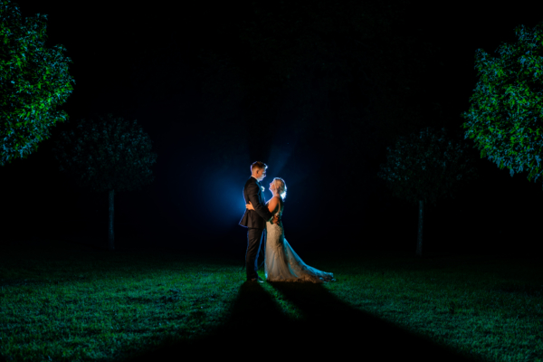 Wedding couple stand together in dark for photo
