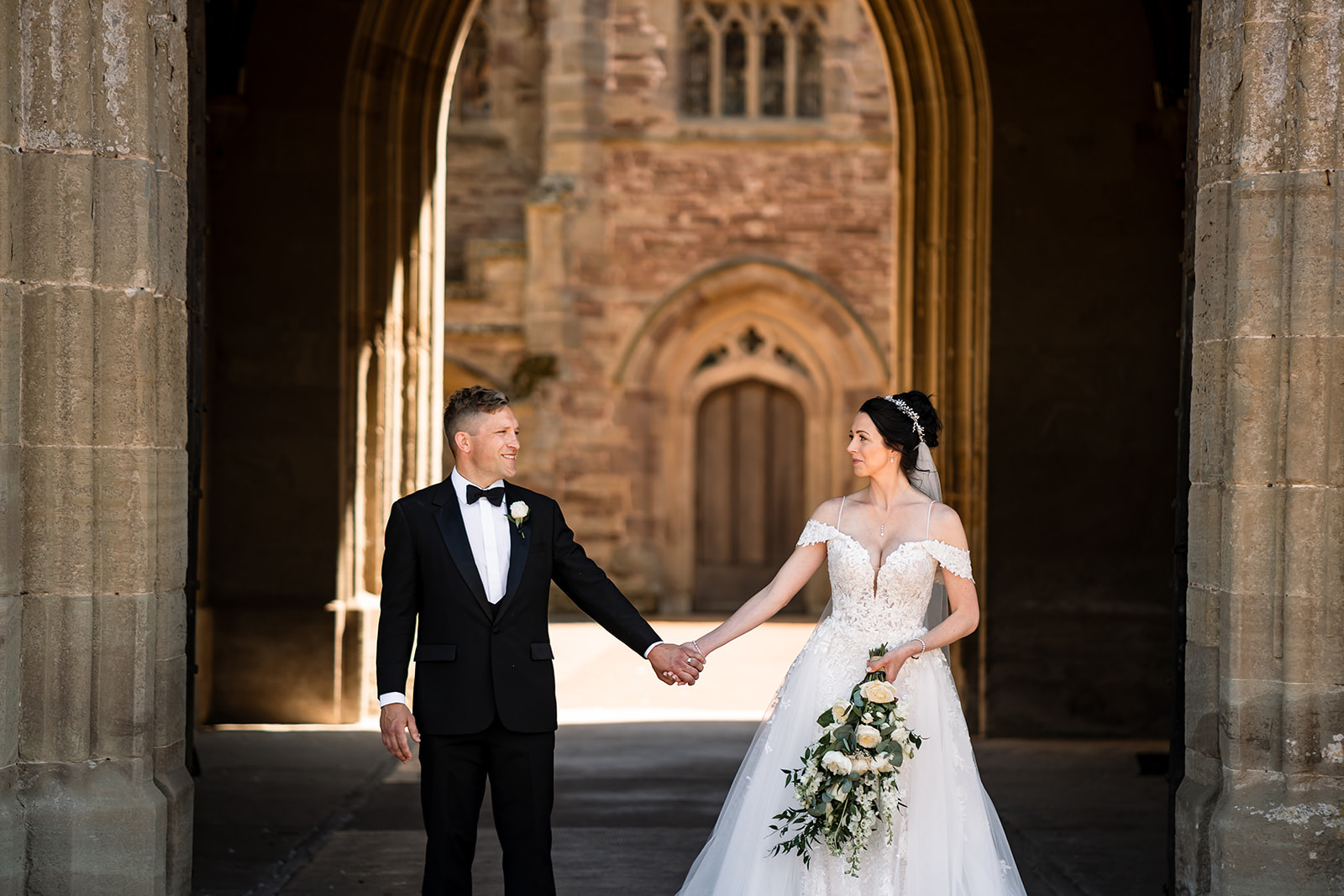 bride and groom holding hands outside the courtyard of Hampton Court Castle wedding venue