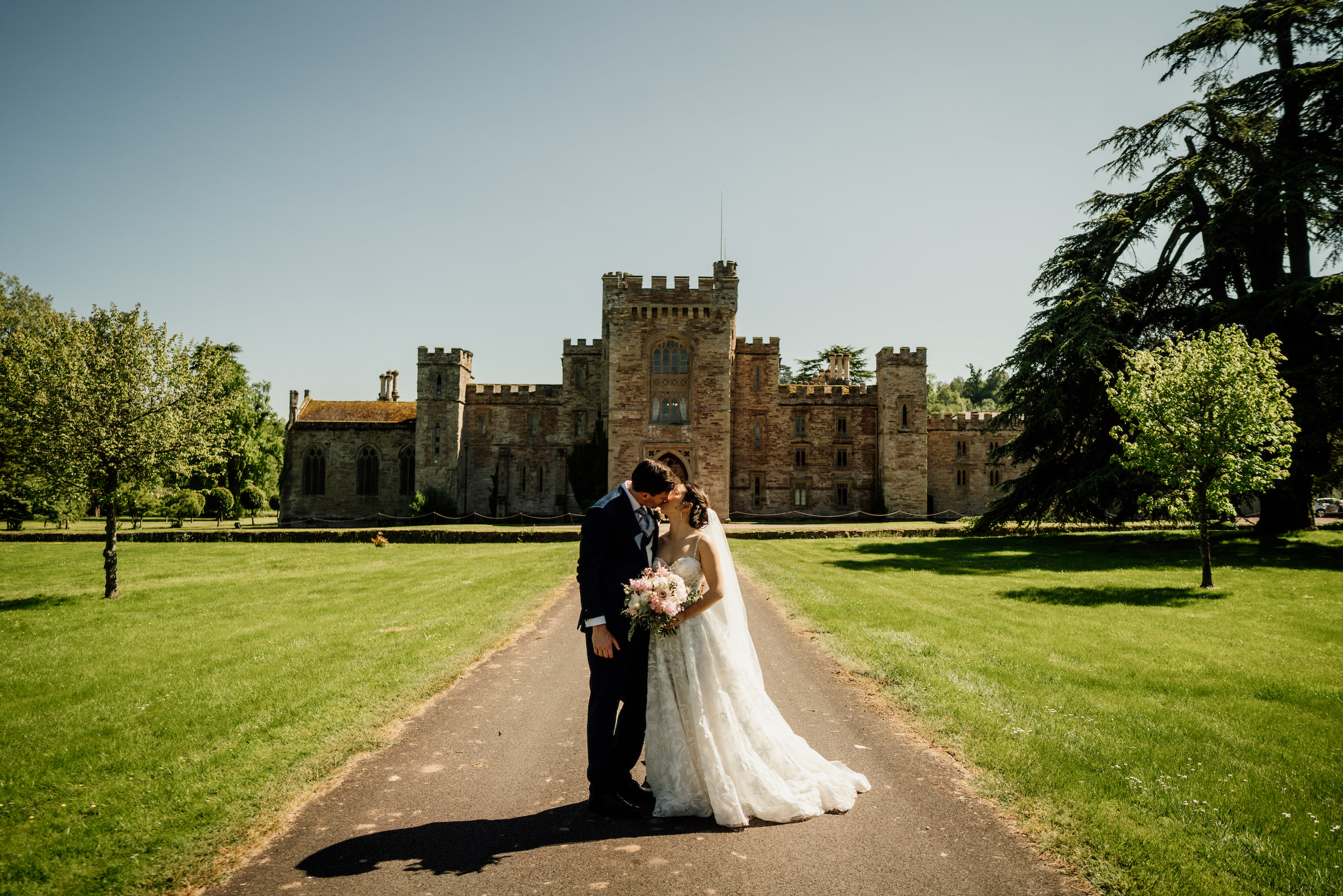 Couple kissing in front of exterior of Hampton Court Castle wedding venue