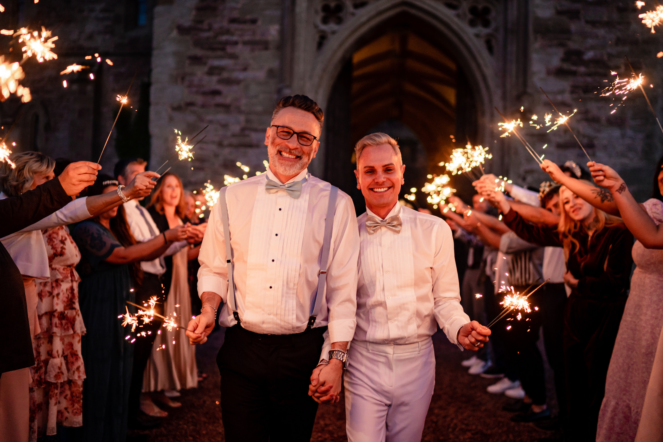 grooms waving sparklers with guests