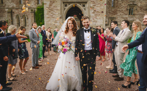 bride and groom covered in confetti thrown by guests at Hampton Court Castle
