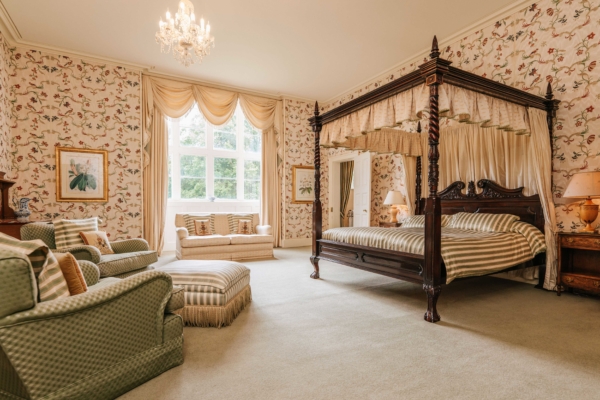 Beautiful period bedroom with four poster bed and silk wallpaper